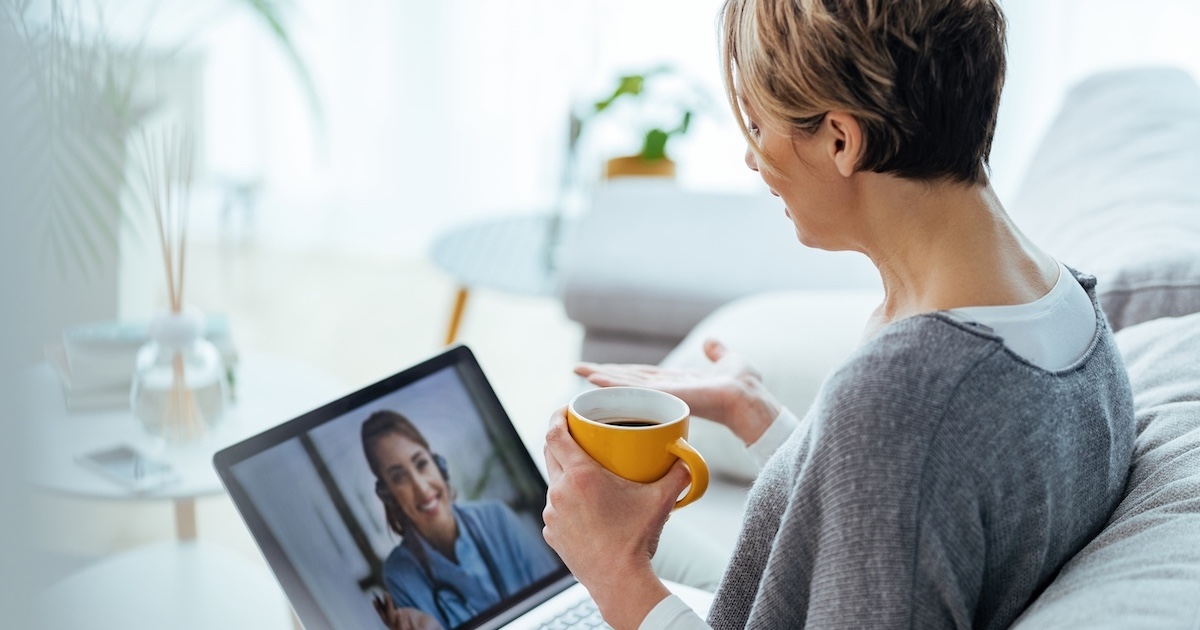 Woman interacting with healthcare professional via laptop 