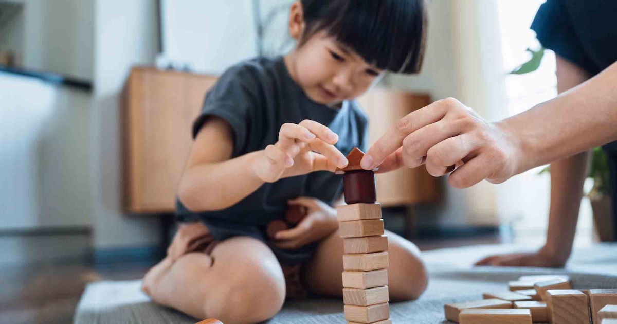 Person playing with blocks while sitting on the floor Person playing with blocks while sitting on the floor