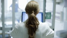 Healthcare provider standing with their back facing the camera in a clinic Healthcare provider standing with their back facing the camera in a clinic