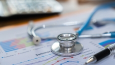 Financial report on a desk with a stethoscope on top Financial report on a desk with a stethoscope on top