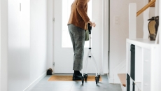A senior adult using a walker opening a door A senior adult using a walker opening a door