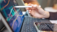 Pen touching a computer screen with financial data Pen touching a computer screen with financial data