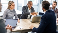 Entrepreneurs shake hands while sitting at a conference table