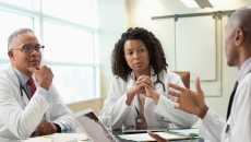 Three people sit around a table Three people sit around a table