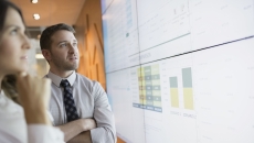 Two people looking at a screen with graphs on it Two people looking at a screen with graphs on it