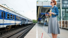 Blind person standing on a train station platform Blind person standing on a train station platform
