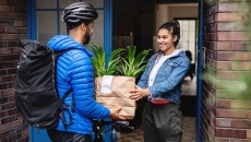 Food delivery person handing a bag to a person standing in their doorway Food delivery person handing a bag to a person standing in their doorway