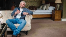 Person sitting on the couch in a hotel room smiling and looking at their phone Person sitting on the couch in a hotel room smiling and looking at their phone