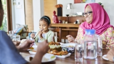 People sitting around a dining room table eating a meal People sitting around a dining room table eating a meal