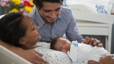 Parents hold infant, one sitting, one laying down Parents hold infant, one sitting, one laying down