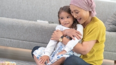 Person and child embracing while sitting on the floor Person and child embracing while sitting on the floor