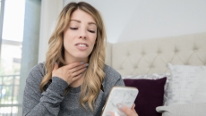 Person on a cellphone holding their throat Person on a cellphone holding their throat