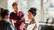 Person in maroon sweater talks with people wearing beige, polka dots Person in maroon sweater talks with people wearing beige, polka dots