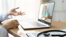 Healthcare provider sitting at a desk with a computer on it and a person on the screen Healthcare provider sitting at a desk with a computer on it and a person on the screen