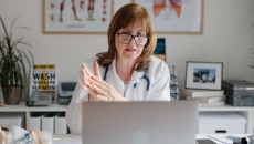 Healthcare professional sitting at a desk looking at a computer Healthcare professional sitting at a desk looking at a computer