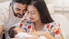 Two people sitting in a bed holding another person Two people sitting in a bed holding another person