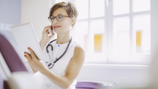Healthcare provider with a stethoscope around their neck while holding a tablet Healthcare provider with a stethoscope around their neck while holding a tablet