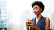Person standing on a city block looking at their phone Person standing on a city block looking at their phone