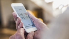 A person holding a phone showing a blood pressure reading A person holding a phone showing a blood pressure reading