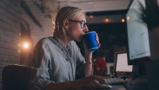 Person sitting at their computer drinking something out of a coffee cup Person sitting at their computer drinking something out of a coffee cup