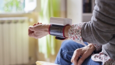 Person sitting on a bed with a wearable on their wrist Person sitting on a bed with a wearable on their wrist
