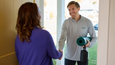 A physical therapist greeting a patient at the door with a yoga mat A physical therapist greeting a patient at the door with a yoga mat