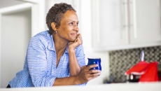 Person leaning against a counter holding a coffee cup Person leaning against a counter holding a coffee cup
