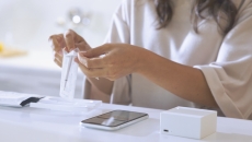 A woman removing the Cue wand from its package with a smartphone and Reader on the table in front of her A woman removing the Cue wand from its package with a smartphone and Reader on the table in front of her