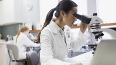 Healthcare professional looking into a microscope Healthcare professional looking into a microscope