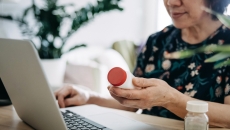 Person looking at a prescription bottle while on a computer Person looking at a prescription bottle while on a computer