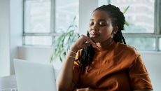Person in orange shirt looking at computer screen Person in orange shirt looking at computer screen