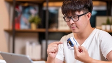 Person in front of laptop with remote medical device on finger Person in front of laptop with remote medical device on finger