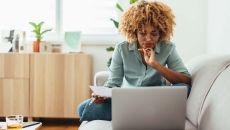 Person sitting on their couch while looking at a computer Person sitting on their couch while looking at a computer