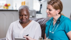 Clinician reviewing healthcare information with a patient with a tablet Clinician reviewing healthcare information with a patient with a tablet