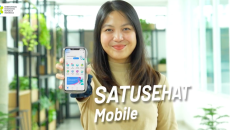 A person holding a mobile phone showing the Satusehat app A person holding a mobile phone showing the Satusehat app