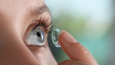 Person inserting a contact lens into their eye Person inserting a contact lens into their eye