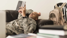 A soldier using a tablet while lying on a sofa. A soldier using a tablet while lying on a sofa.