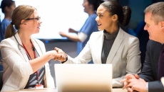 Businesspeople shaking hands in front of a laptop Businesspeople shaking hands in front of a laptop