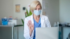 A doctor wearing a mask talking to a patient via telehealth A doctor wearing a mask talking to a patient via telehealth