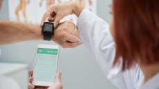 A doctor helping a patient sync heart rate data from a wearable to a smartphone. A doctor helping a patient sync heart rate data from a wearable to a smartphone.