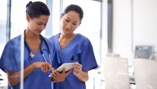 Two nurses using a tablet to review medical records. Two nurses using a tablet to review medical records.