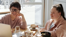 A person with Down syndrome with a friend watching from a laptop