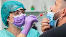 Female doctor in protective workwear taking nose swab test from middle aged man wearing protective face mask Female doctor in protective workwear taking nose swab test from middle aged man wearing protective face mask
