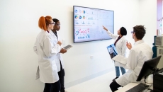 A team of researchers looking at charts on a monitor