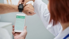 A doctor showing a senior patient how to synchronize their health app in a smartphone and a smartwatch A doctor showing a senior patient how to synchronize their health app in a smartphone and a smartwatch