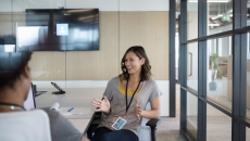 Two people sitting at a tablet talking to each other