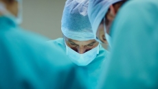 Three healthcare professionals performing surgery