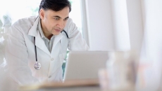 A doctor using a laptop to write referrals A doctor using a laptop to write referrals