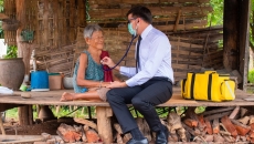 A rural doctor checking an elderly person's breathing with a stethoscope in a hut