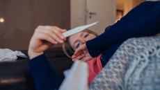 A sick woman looking at a thermometer A sick woman looking at a thermometer